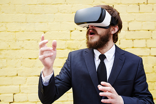 Young man in suit and vr headset enjoying virtual reality