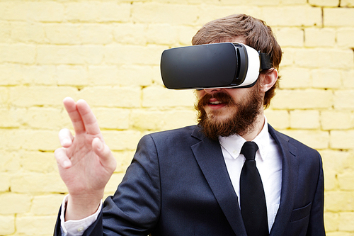 Businessman in vr goggles touching imaginary button on display