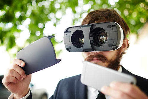 Businessman putting his smartphone in vr goggles or taking it out