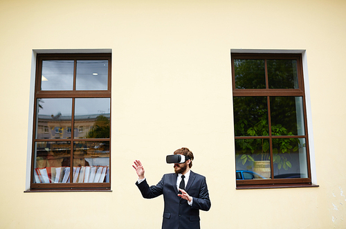 Businessman in vr headset standing against wall of house between two windows