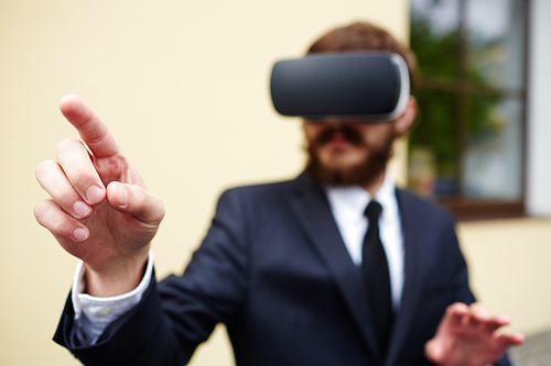 Businessman with augmented reality headset touching imaginary button to start vr game