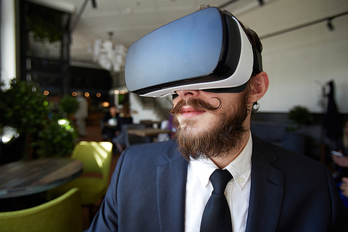Bearded businessman in suit and vr headset watching curious video