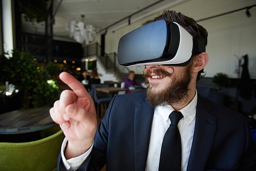 Businessman in vr goggles pointing at something curious