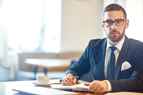 Confident trader in elegant suit sitting in cafe