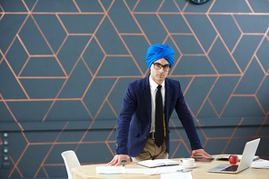 Serious businessman leaning at workplace