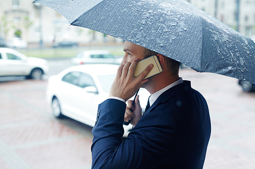 Broker under umbrella phoning in the street