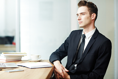 Inspired businessman thinking of new project or forthcoming vacation by his workplace