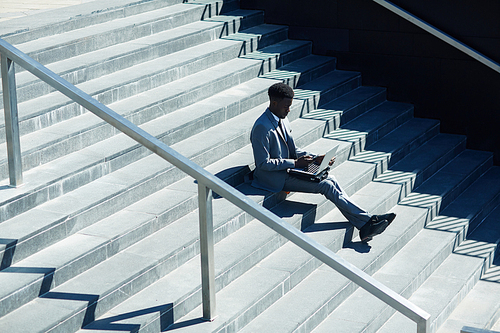 businessman with laptop sitting on staircase in urban  and networking