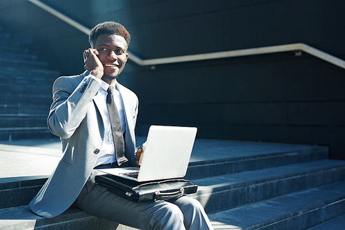 Smiling agent with laptop speaking to client on smartphone