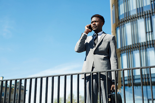 Manager in suit speaking by cellphone in urban environment