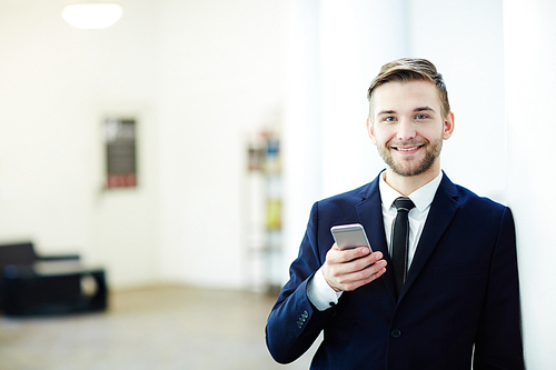 Happy young man with smartphone wearing suit