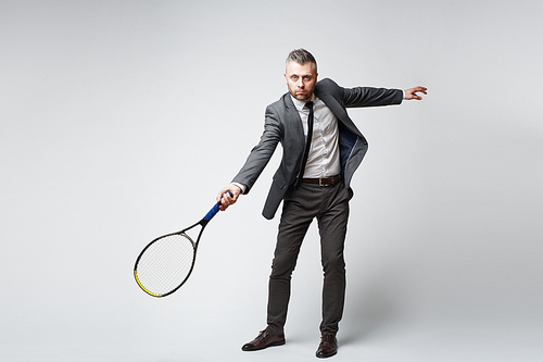 Full length portrait of confident middle aged man in business suit  while playing tennis