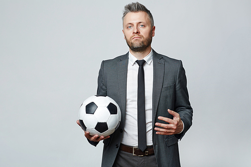 Waist up studio portrait of middle aged man with grey hair holding soccer ball and 
