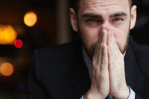 Portrait of modern bearded businessman  with red teary eyes, stressed and tired against black background, closing his mouth with hands