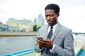 mobile businessman messagingin urban  during travel by water