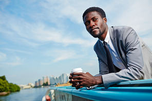 Calm businessman with drink contemplating during travel by steamship