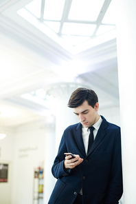 Businessman with smartphone communicating through messaging