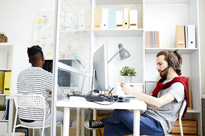 Serious thoughtful hipster multiethnic operators in casual clothing wearing headsets and answering call while working in IT support company