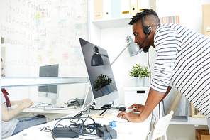 Serious guy in headset concentrating on reading online data on computer screen and talking to clients