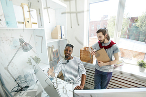 Two hipster guys in casualwear looking at computer screen and discussing data or software language