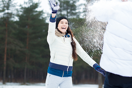 Laughing girl having fun with her boyfriend during snowball play on winter day