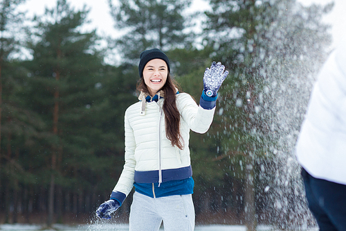 Young woman laughing during snowball play with her boyfriend on weekend outdoors