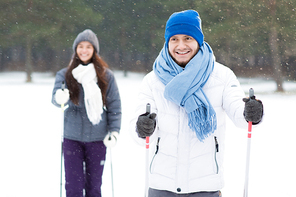 Young sportive couple in activewear spending leisure in skis in winter forest or park