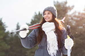 Healthy and active young female holding skis while looking for good place to ski