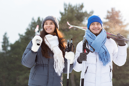Cheerful young man and woman with skis spending winter weekend in park
