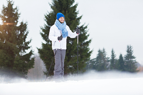 Happy guy in warm winter activewear moving forwards on skis while enjoying weekend in park