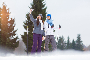 Modern young and active couple on skis making selfie for social networks on winter day