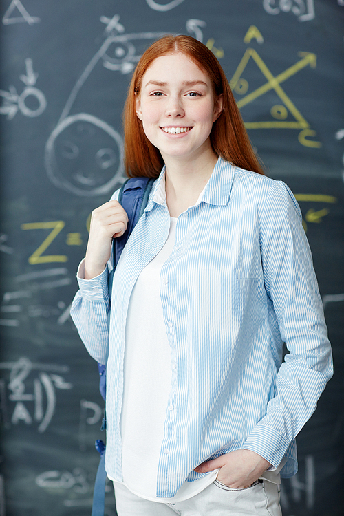 Teenage student in casualwear  with toothy smile against blackboard