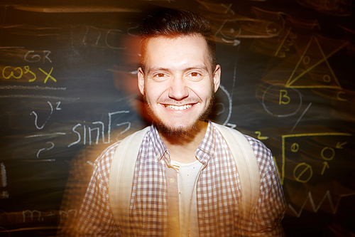 Cheerful student with toothy smile  against blackboard with notes