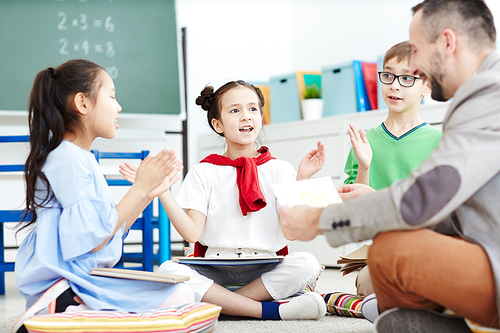 Diligent schoolkids learning rhymes by heart while repeating them after teacher