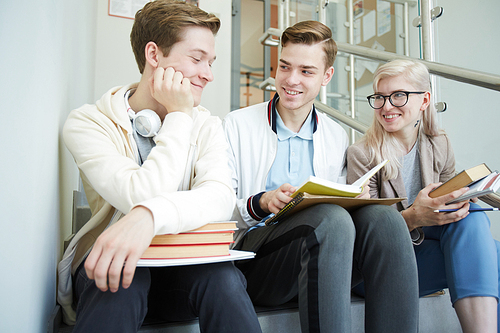 One of friendly guys with open book discussing the story with groupmates at break