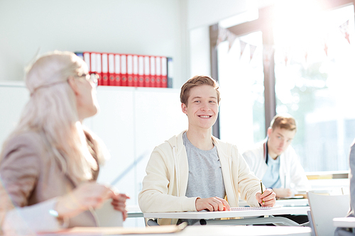 Smiling guy looking at one of groupmates at lesson during individual work