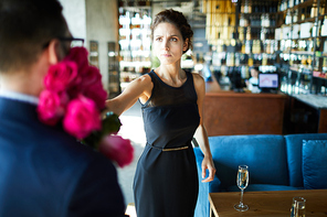 Angry young brunette woman giving bunch of roses back to her boyfriend after quarrel