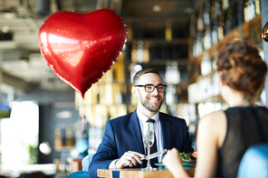 Happy young man looking at his girlfriend during lunch in restaurant on saint valentine day