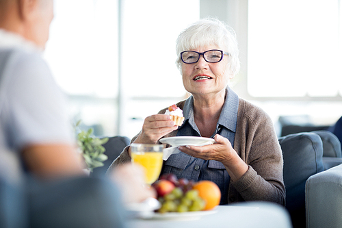 Portrait of modern senior woman enjoying dessert cake while chatting with husband in cafe