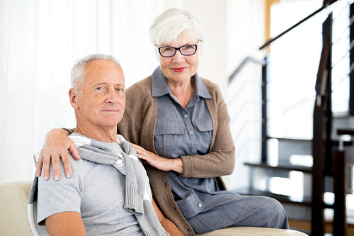 Portrait of loving senior couple posing together on sofa in modern interior and , copy space