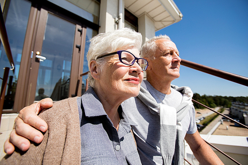 Portrait of modern senior couple embracing outdoors in sunlight smiling happily