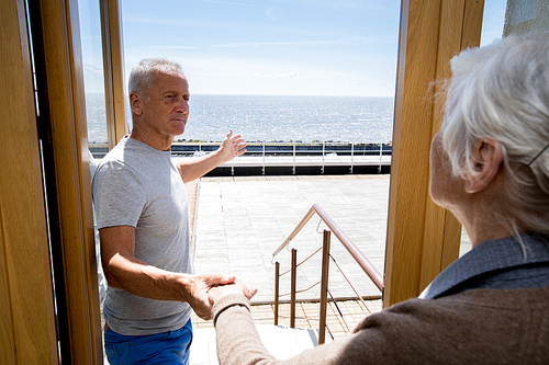 Senior man inviting woman to go out for chill by seaside during summer vacation
