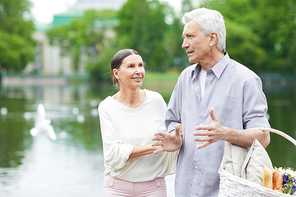 Aged grey-haired man and his wife discussing where to go for picnic in park