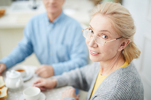 Blond woman in eyeglasses  while having breakfast with husband at home