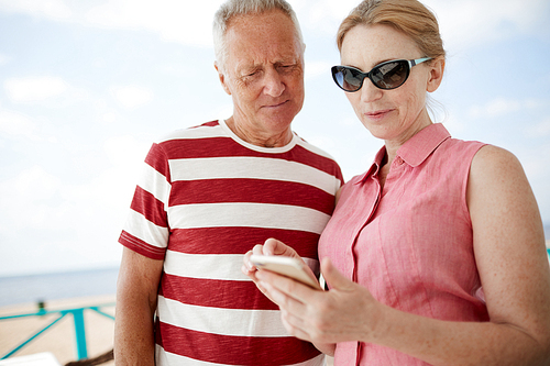 Woman in sunglasses and her husband reading notification in her smartphone