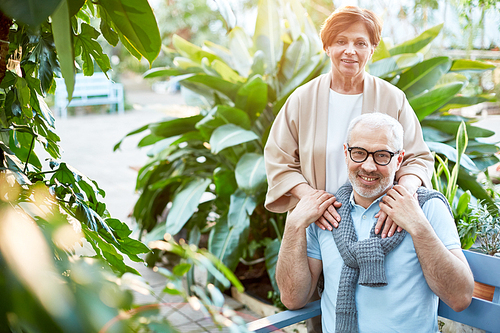 Mature husband holding his wife hands and both  while spending leisure in orangery or garden