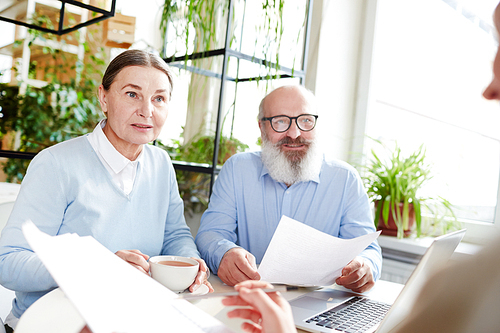 Senior couple having discussion of financial documents with agent before signing