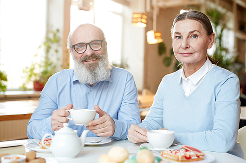 Happy mature man and woman  while spending time in cafe by dessert