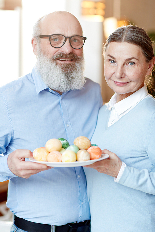 Happy mature man and woman with heap of easter eggs 