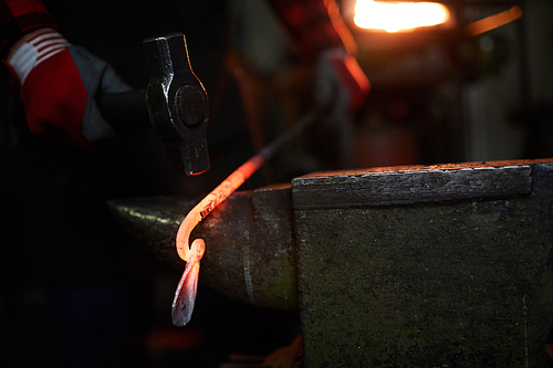 End of molten iron workpiece on anvil during forging process in blacksmith workshop